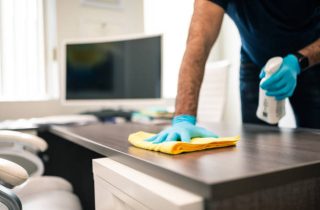 Man disinfecting an office desk